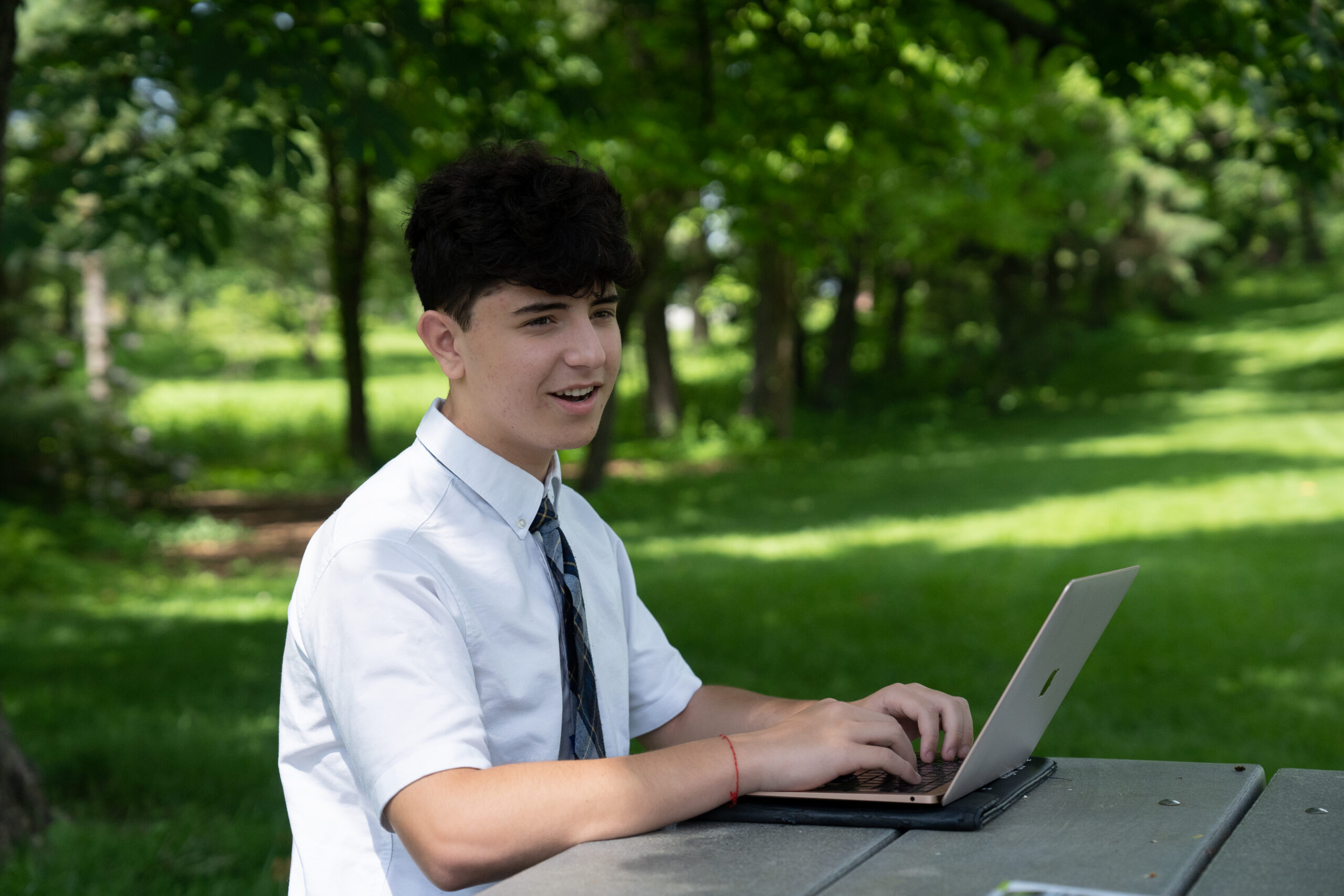 A Star Academy student working on a laptop outdoors